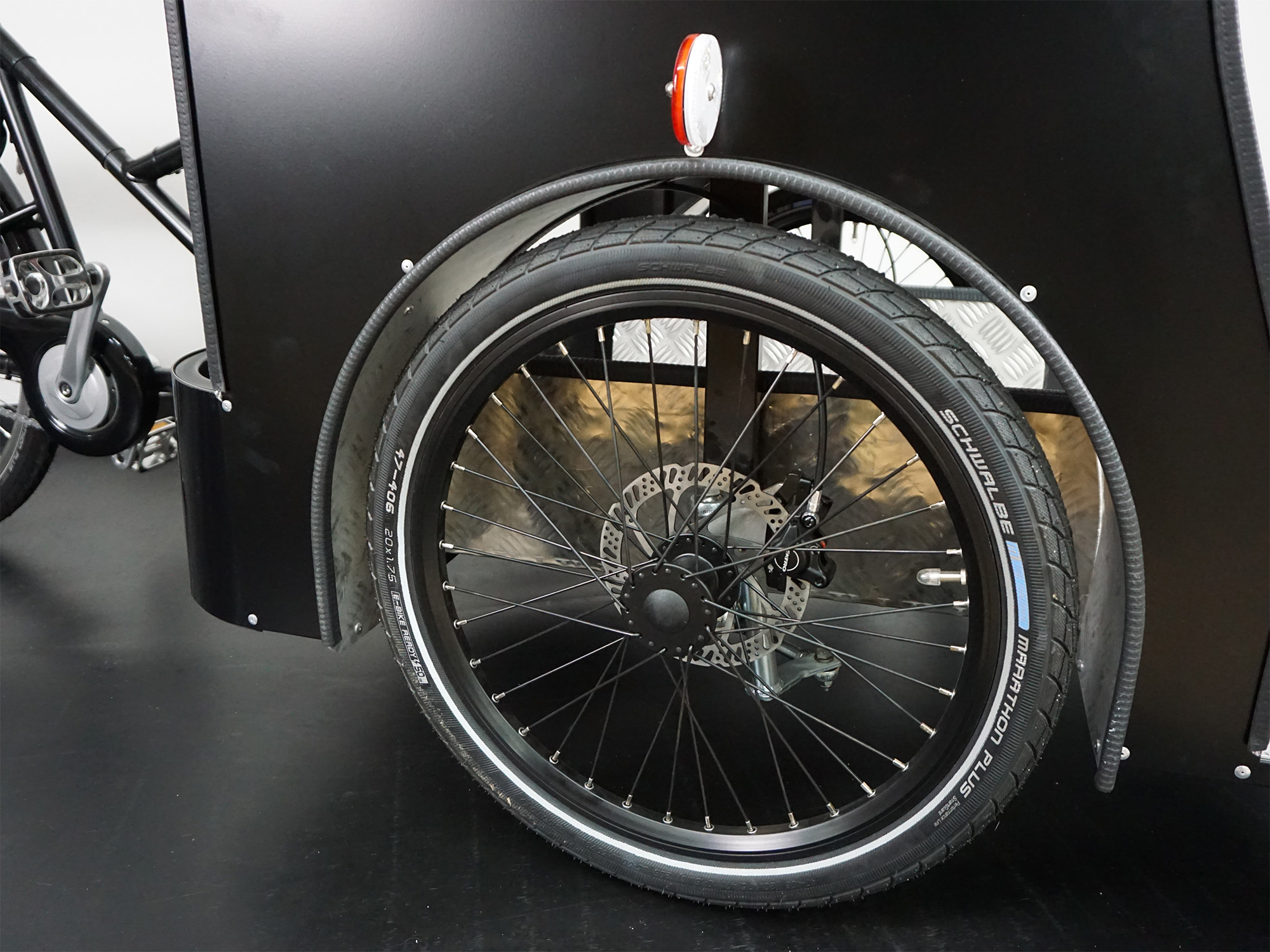 Seitenansicht eines Transportrads mit großem Laufrad, Scheibenbremse, Schutzblech und stabiler Transportbox.