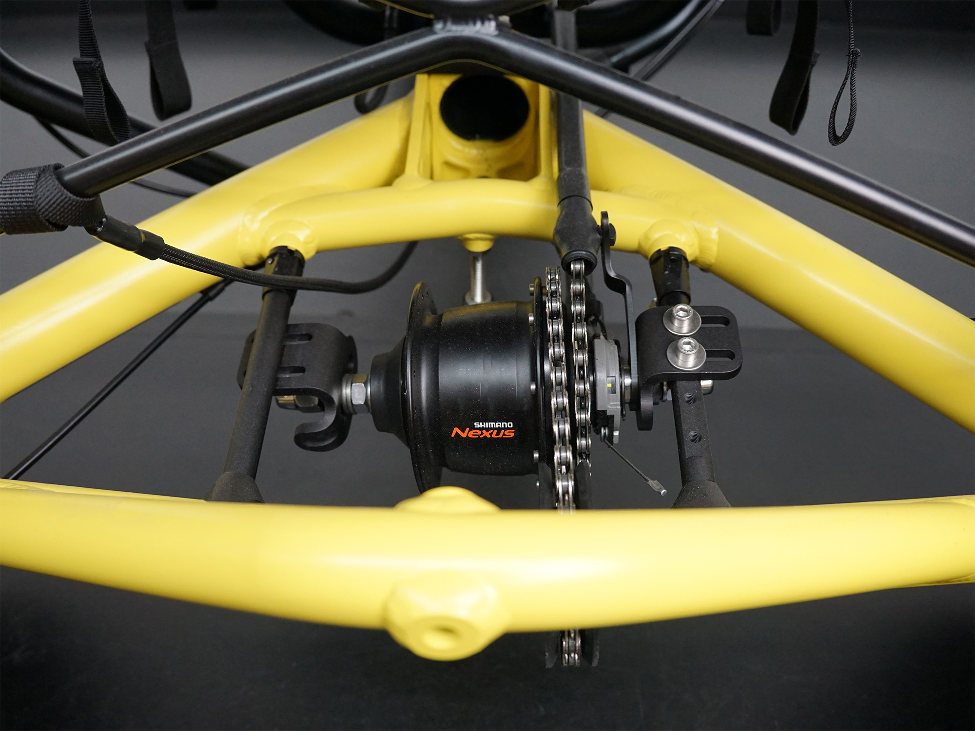 Nahaufnahme der Hinterradnabe eines Liegerads mit gelbem Rahmen, Shimano Nexus Schaltung und Kettentrieb.