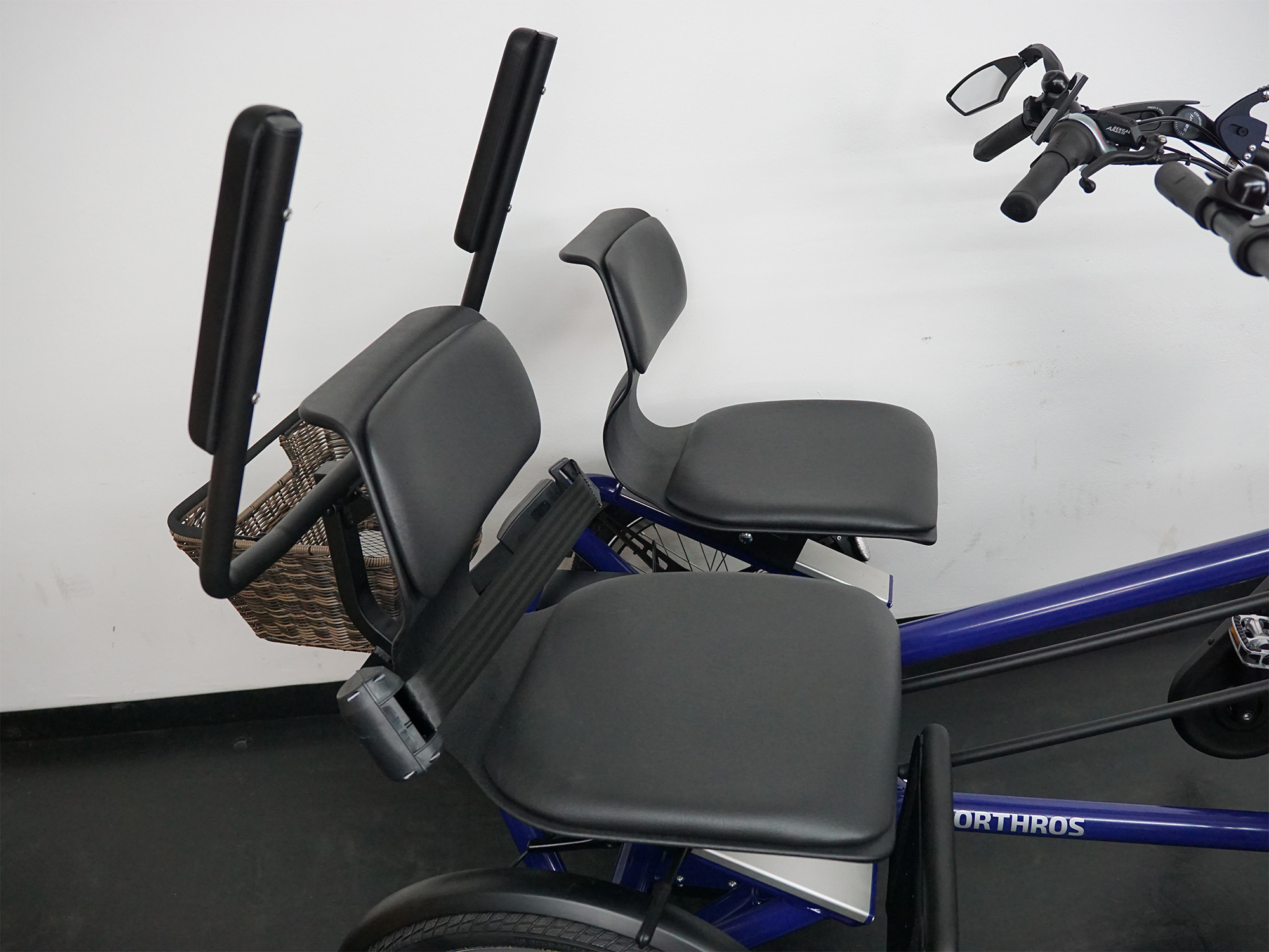 Zwei gepolsterte Sitze mit Armlehnen auf einem Spezialfahrrad für gemeinsame Mobilität.