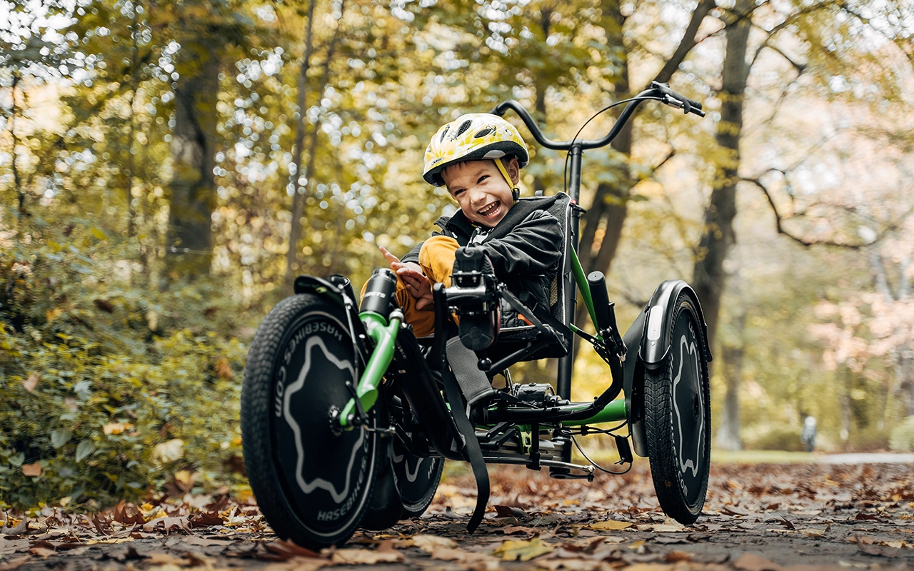kind mit helm lacht auf grünem hase-liegerad