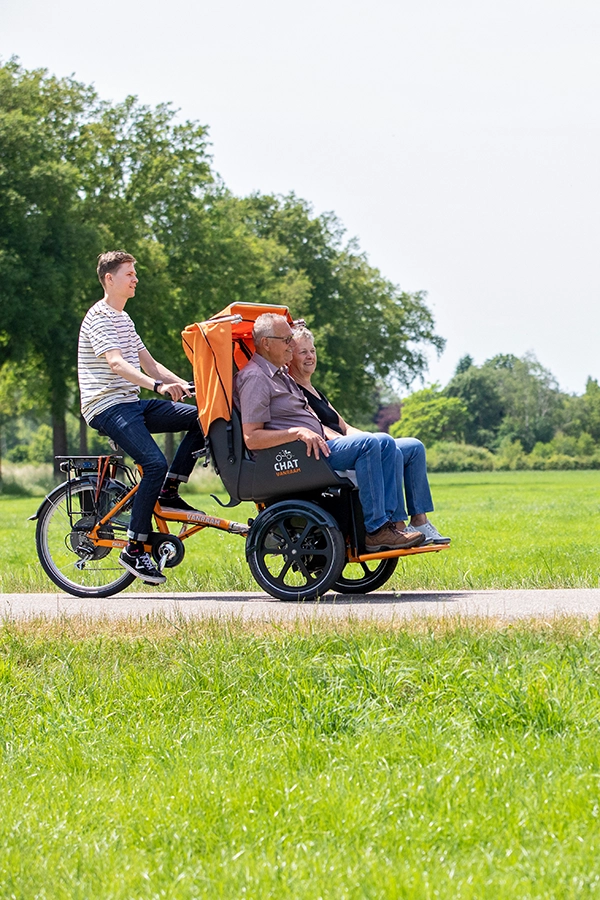 Ein Mann fährt eine Rikscha wo eine Frau und ein Mann vorne drin sitzen