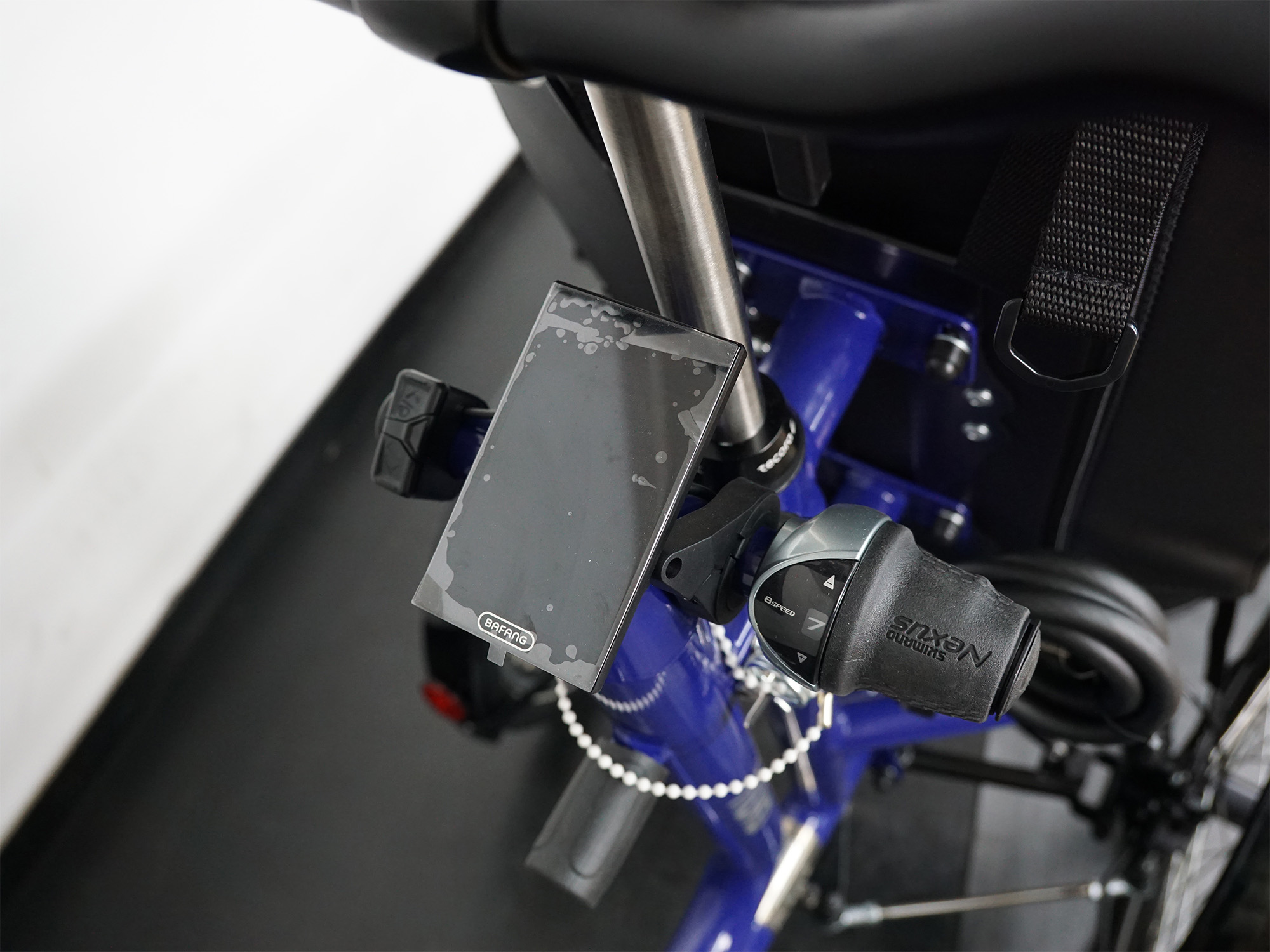 Nahaufnahme mit Schloss, Smartphone Halterung und Rücklichthalter an blauem Therapieradrahmen.