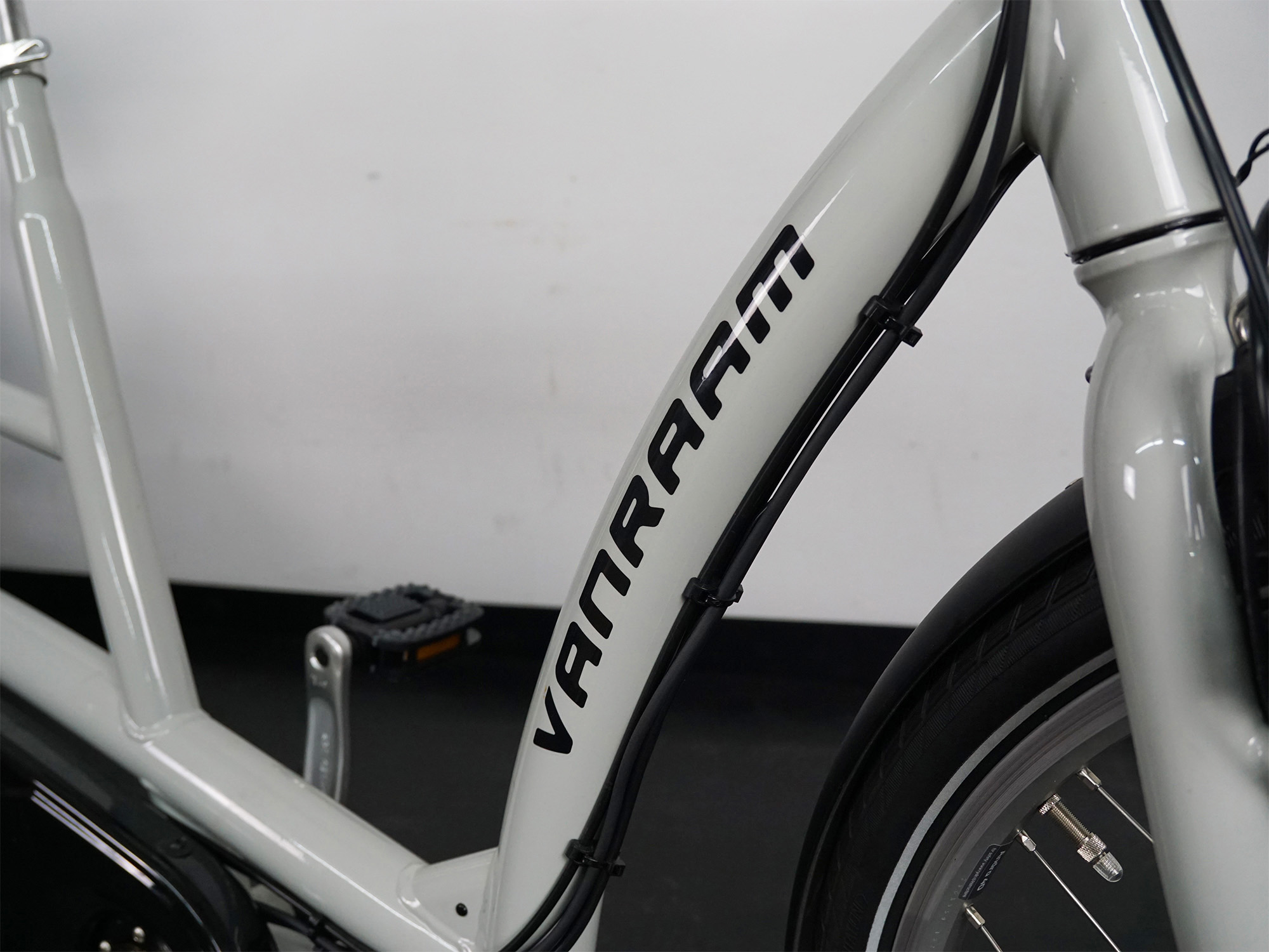 Rahmenausschnitt eines Van Raam-Fahrrads mit Markenlogo, Kabelzügen und Vorderrad