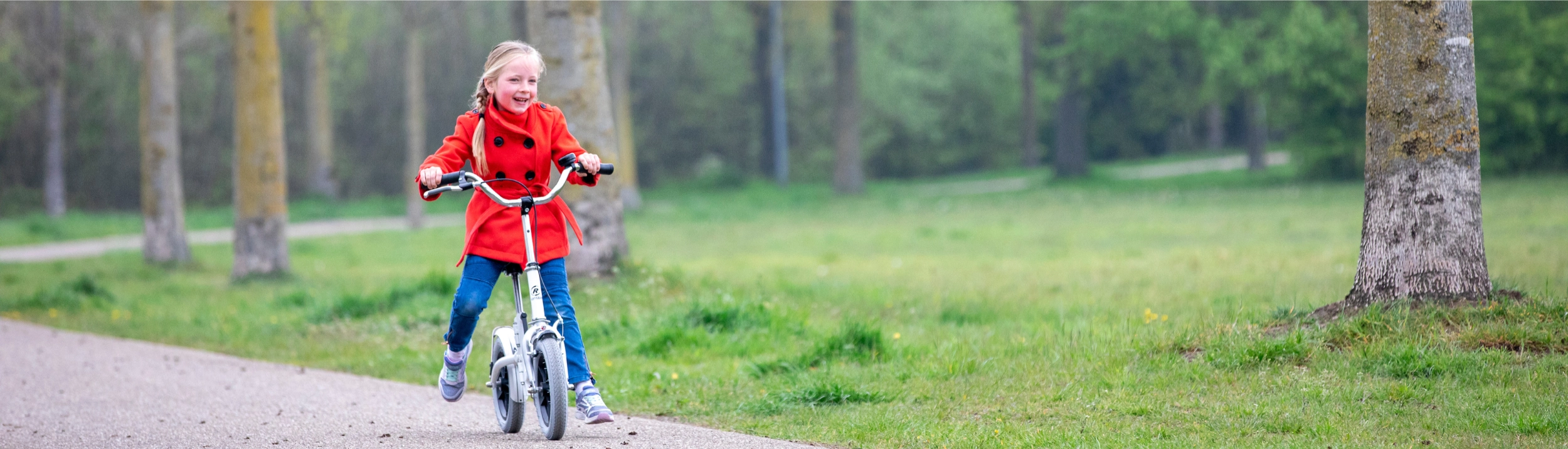 Ein Kind läuft mit Hilfe eines Laufrades in der Natur