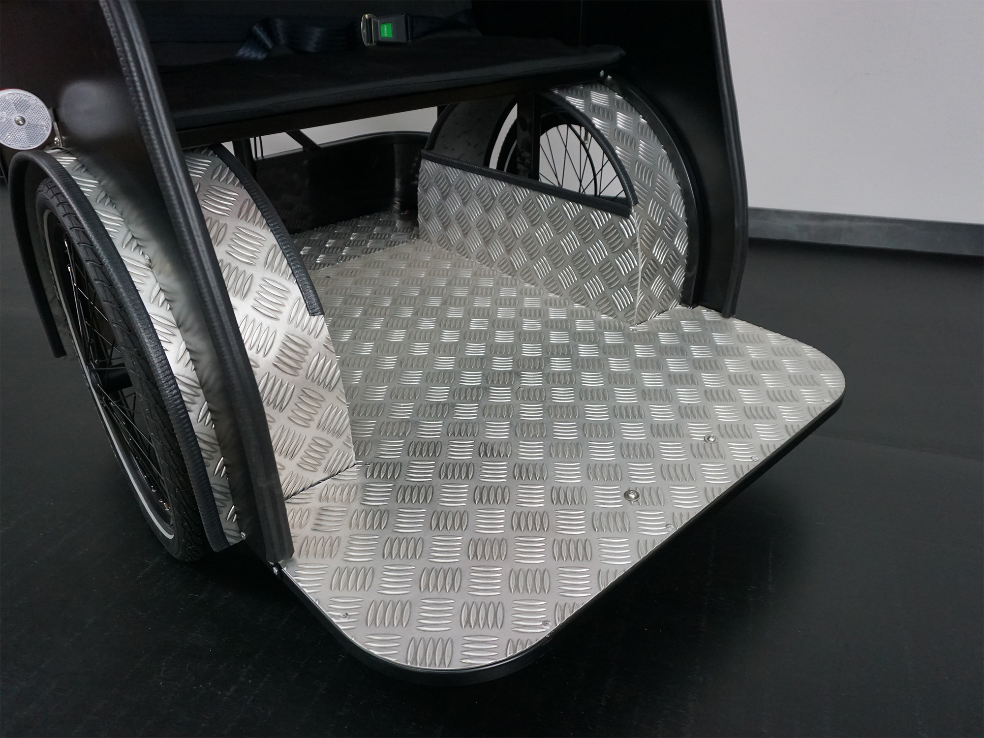 Nahaufnahme einer Transportplattform mit rutschfestem Riffelblechboden, seitlichen Abdeckungen und integrierten Rädern.