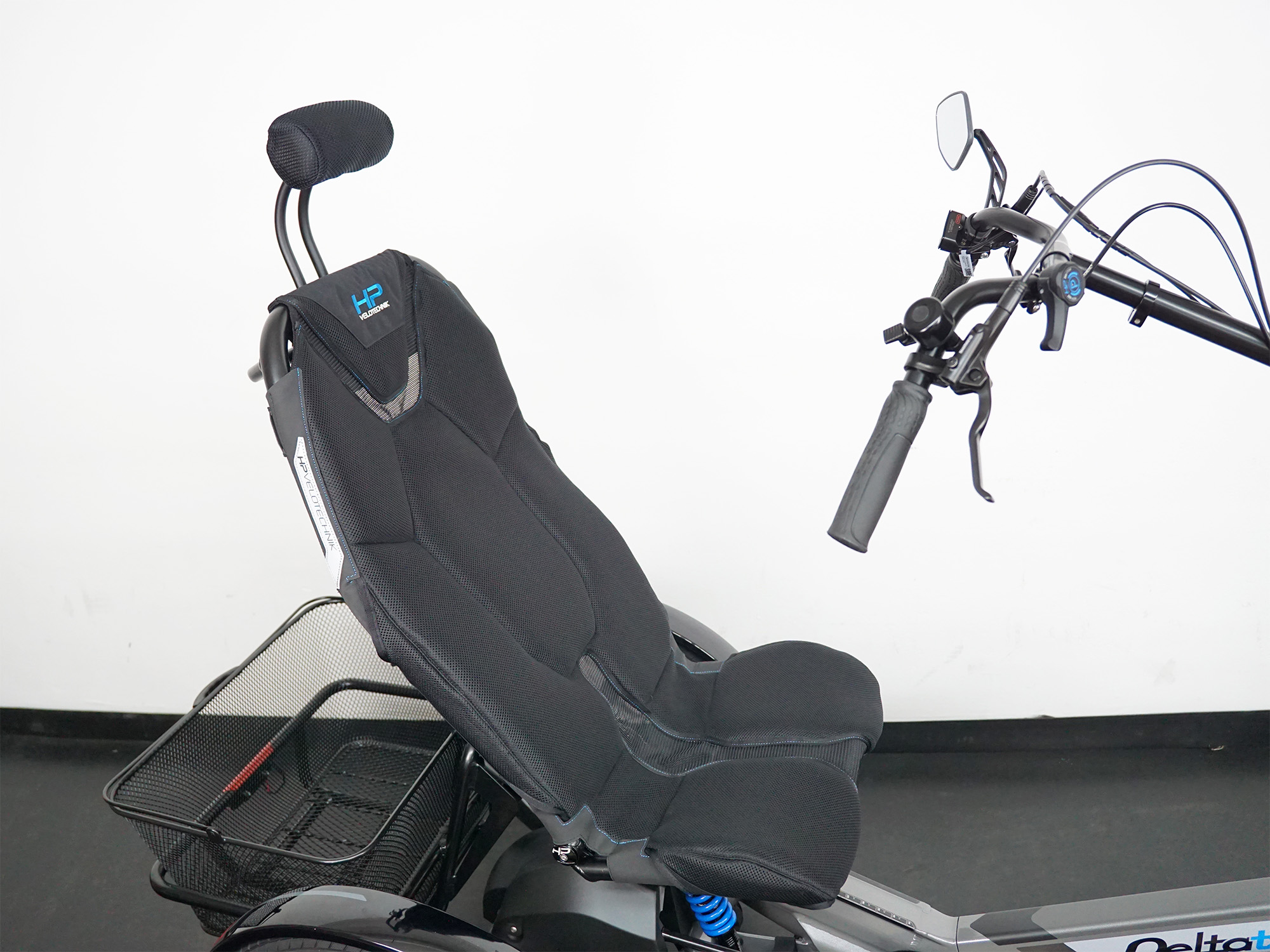 Sitz und Lenker eines Liegedreirads mit Kopfstütze, schwarzem Netzsitz und seitlichem Lenkergriff mit Spiegel.