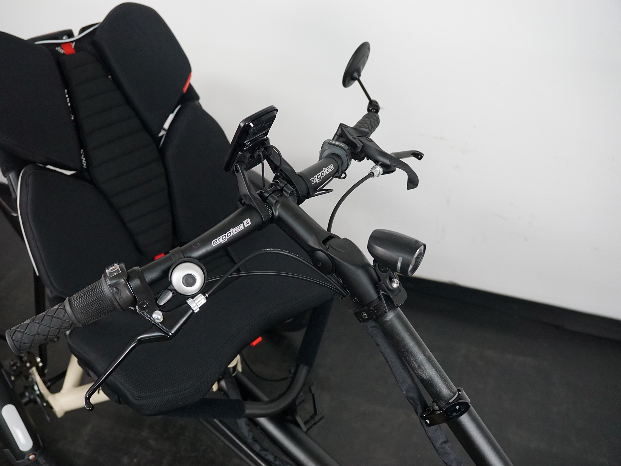Liegedreirad mit gepolstertem Netzsitz, Lenker mit Klingel, Display, Spiegel und Frontlicht – komfortabel ausgestattet.