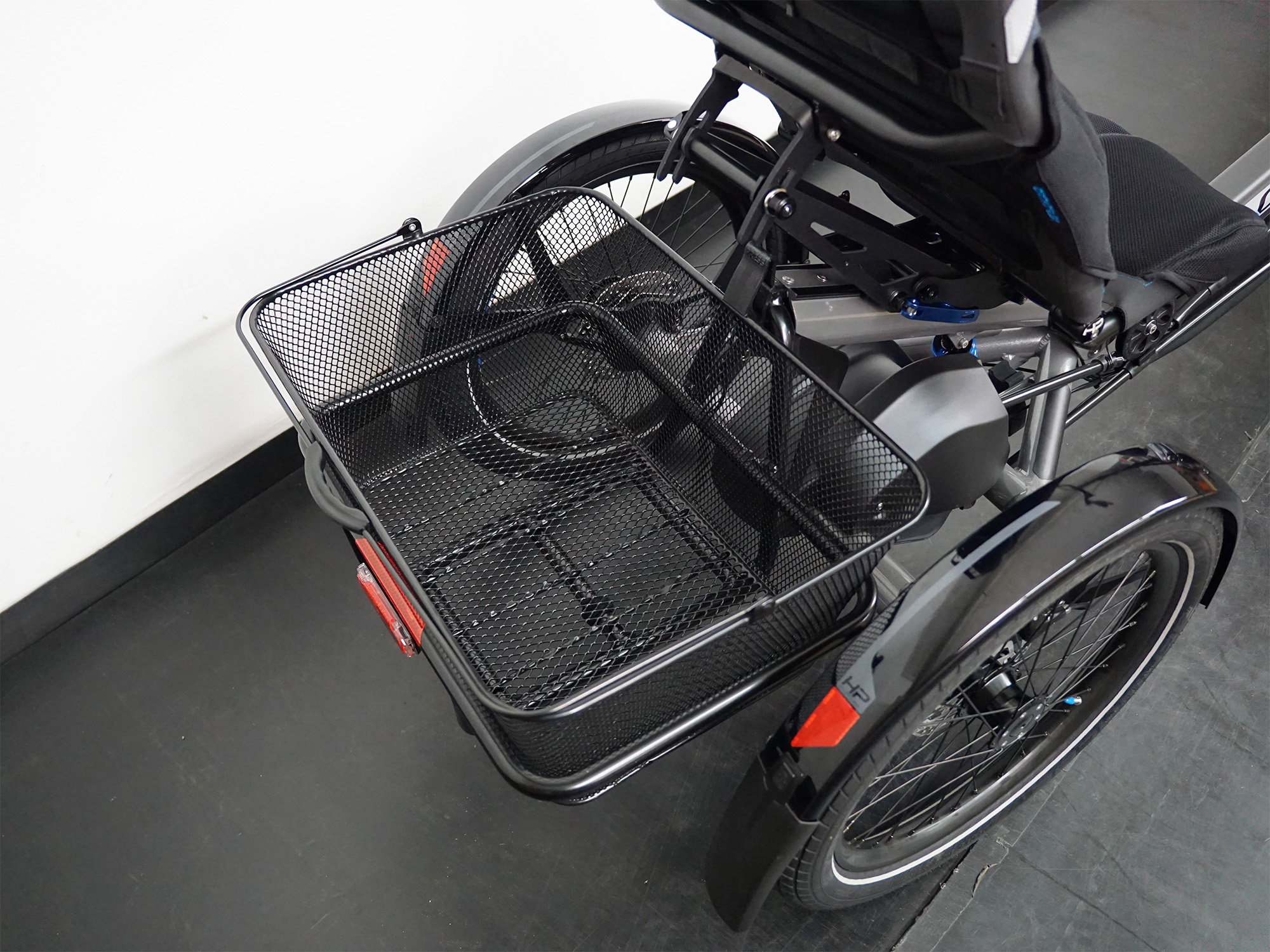 oßer schwarzer Gepäckkorb aus Metall am Heck eines Liegedreirads, montiert über der Hinterachse.