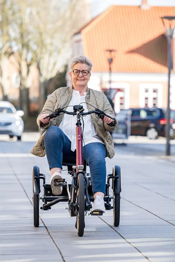 Frau fährt ein Dreirad und lächelt dabei