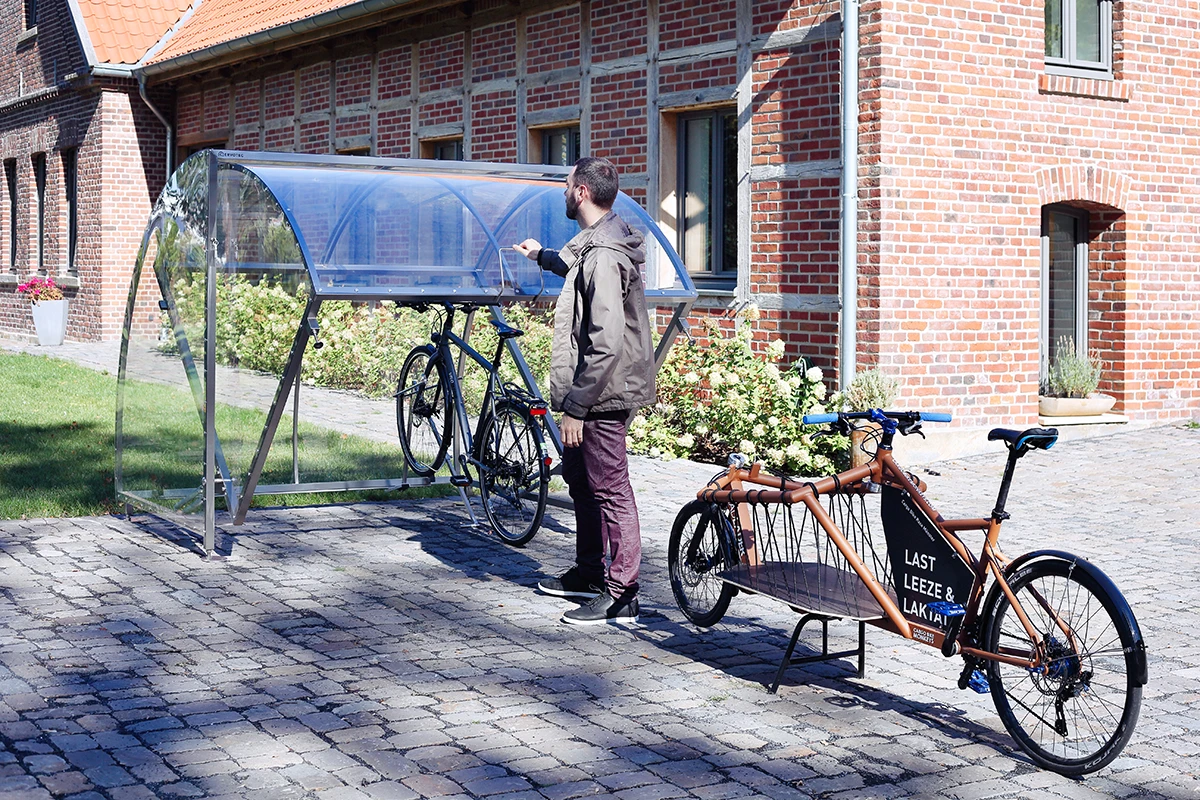 mann schließt sein fahrrad an einem überdachten ständer a